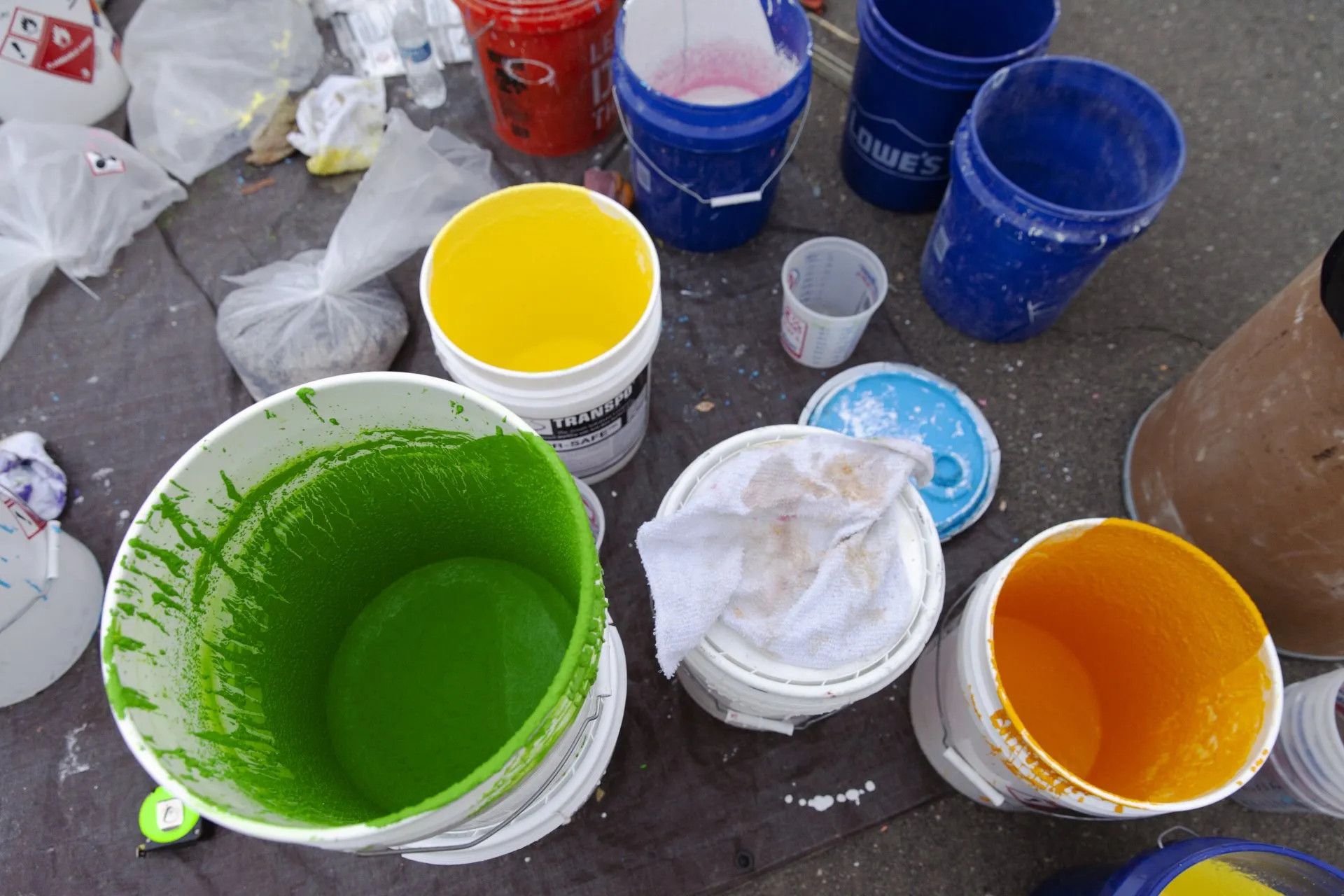 A bunch of buckets filled with different colors of paint