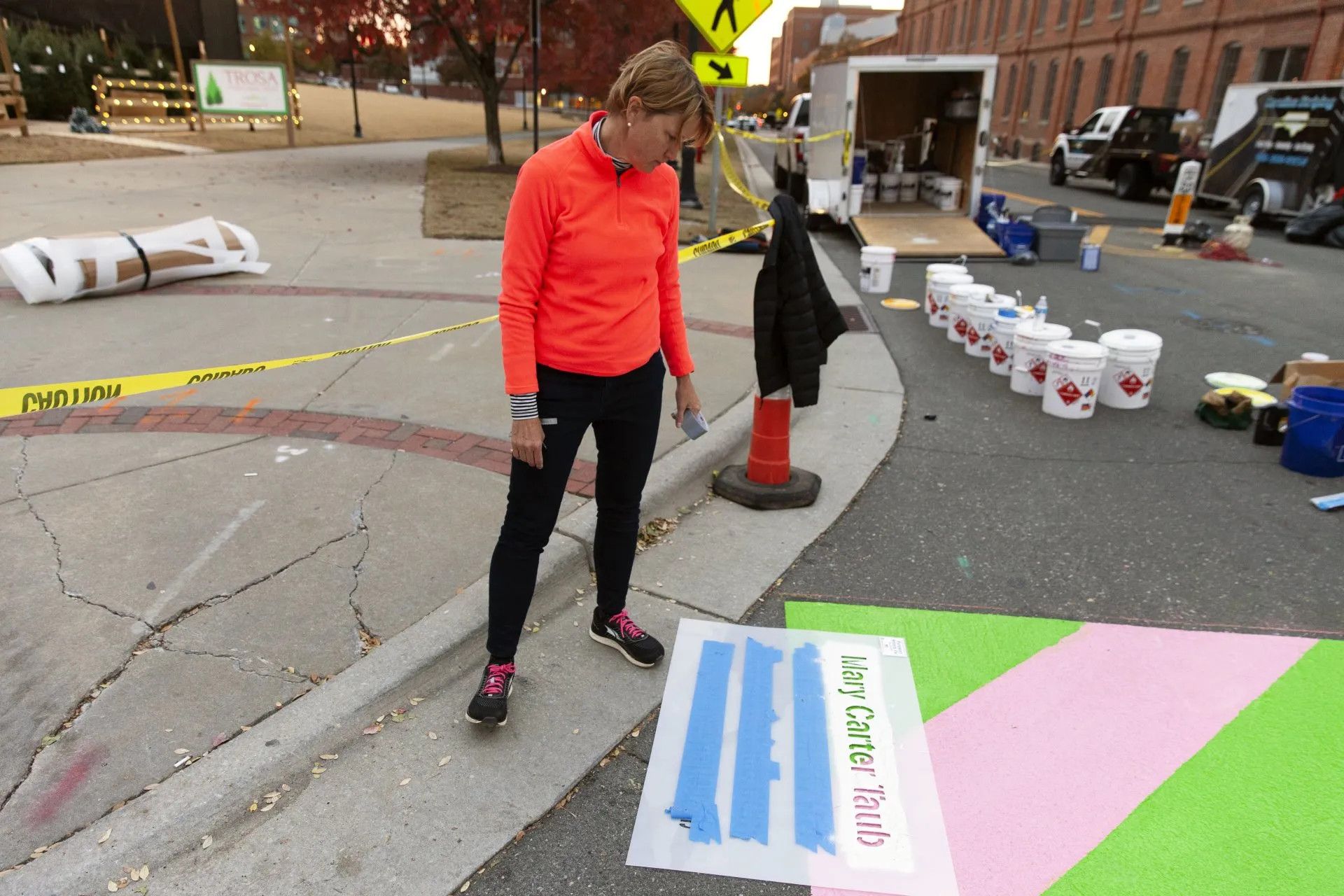 A woman in an orange shirt is standing next to a sign that says welcome sub