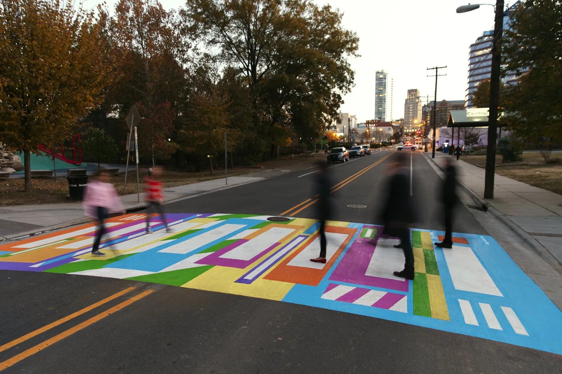 A group of people are crossing a rainbow painted crosswalk
