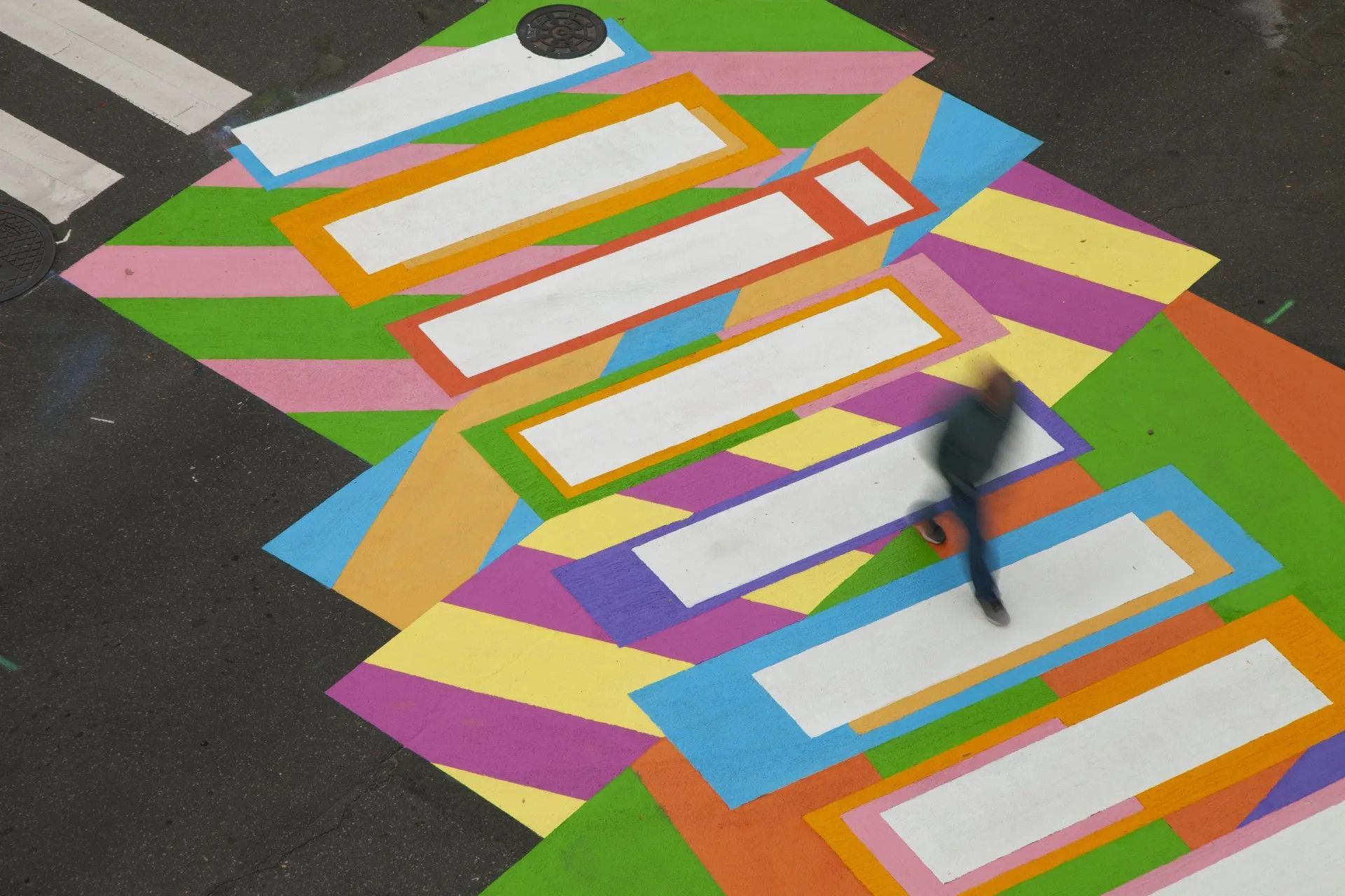 A person is walking across a colorful crosswalk