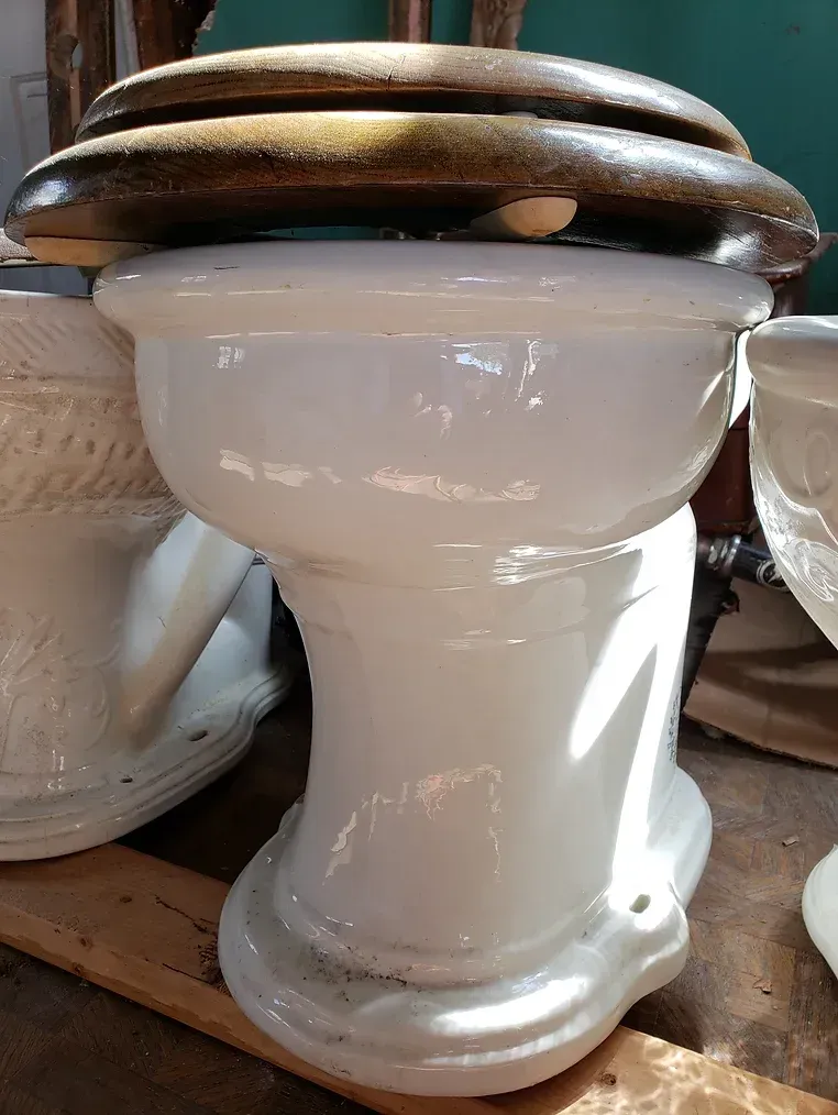 A white toilet with a wooden seat is sitting on top of a wooden table.