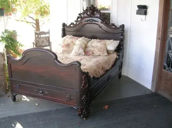 A bed is sitting on a porch next to a chair