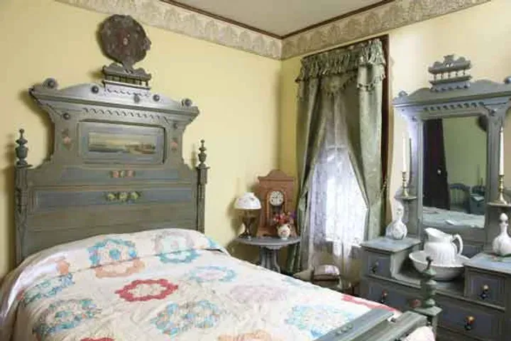 A bedroom with a bed , dresser , mirror and clock.