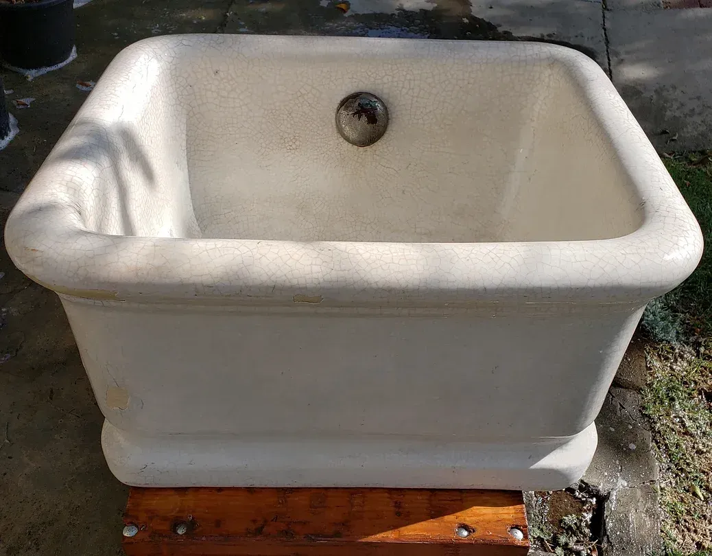 A white foot bath is sitting on top of a wooden table.