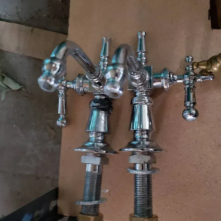 A pair of chrome faucets are sitting on a wooden table