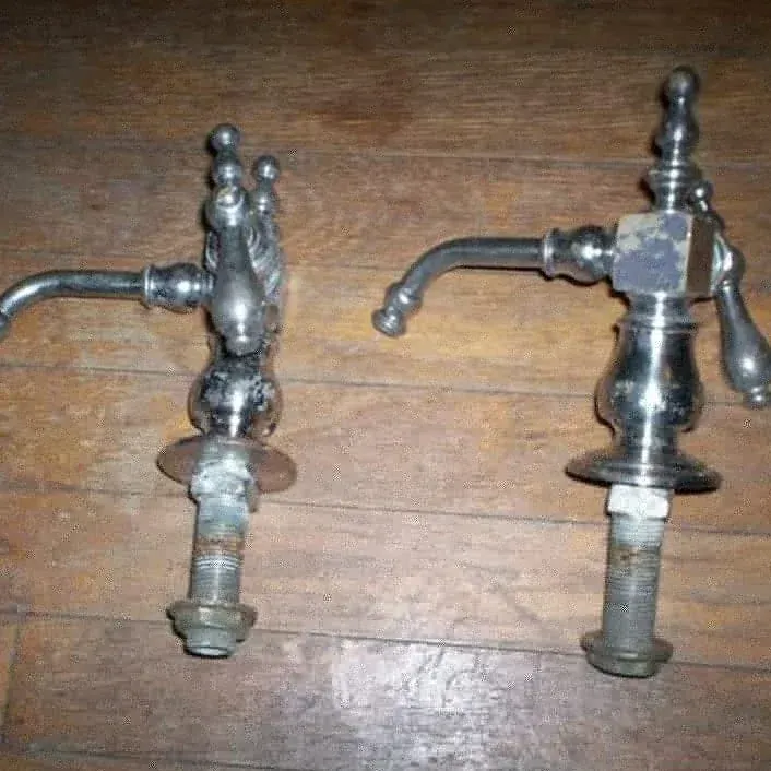 A pair of faucets are sitting on a wooden floor