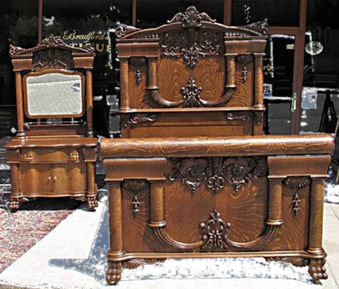 A wooden bed with a mirror and nightstand next to it