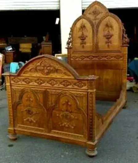 A carved wooden bed is sitting in a garage