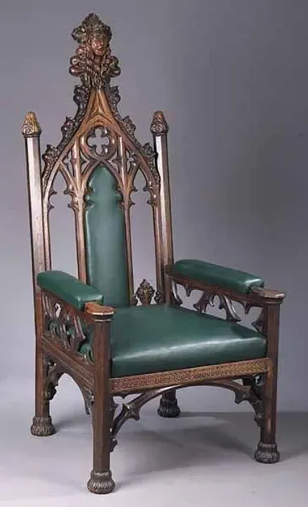 A wooden chair with a green seat and arm rests