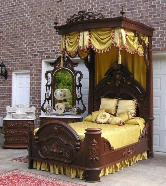 A bed with a canopy and a mirror in front of a brick wall