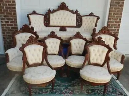 A set of chairs and a couch are sitting on a rug in front of a garage door.