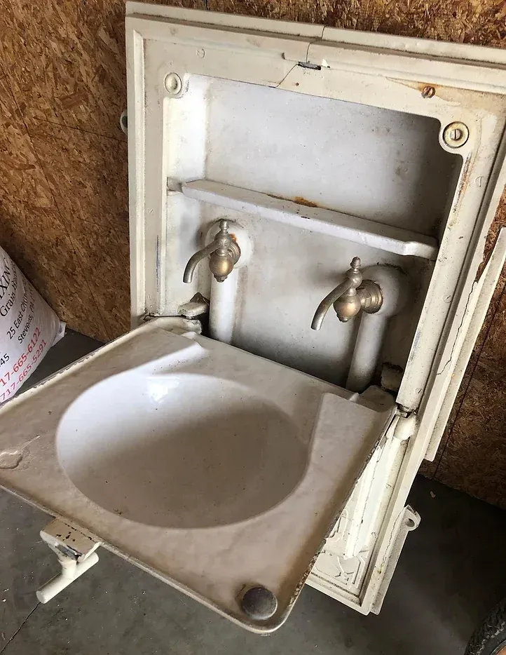 A bathroom sink with two faucets and a shelf