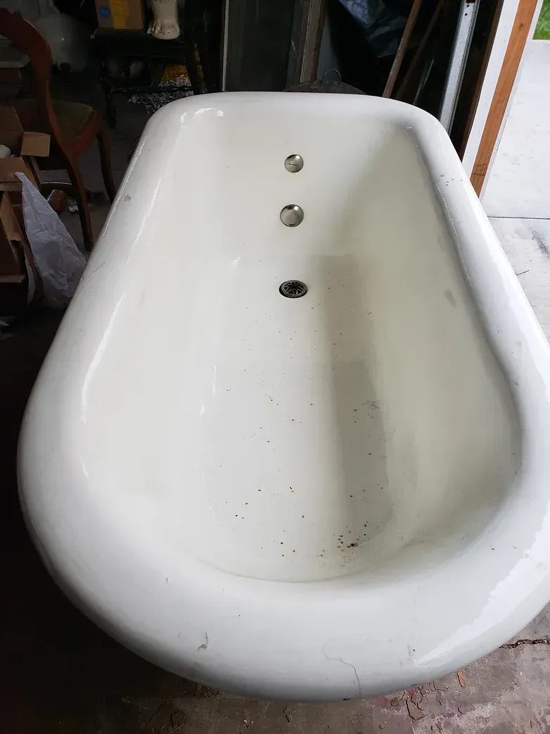 A white bathtub is sitting on the floor in a garage.