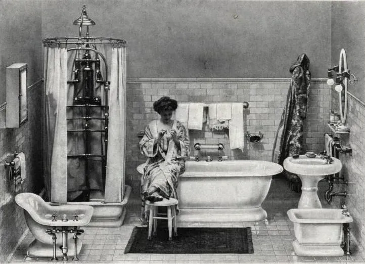 A woman sits on a stool in a bathroom next to a bathtub