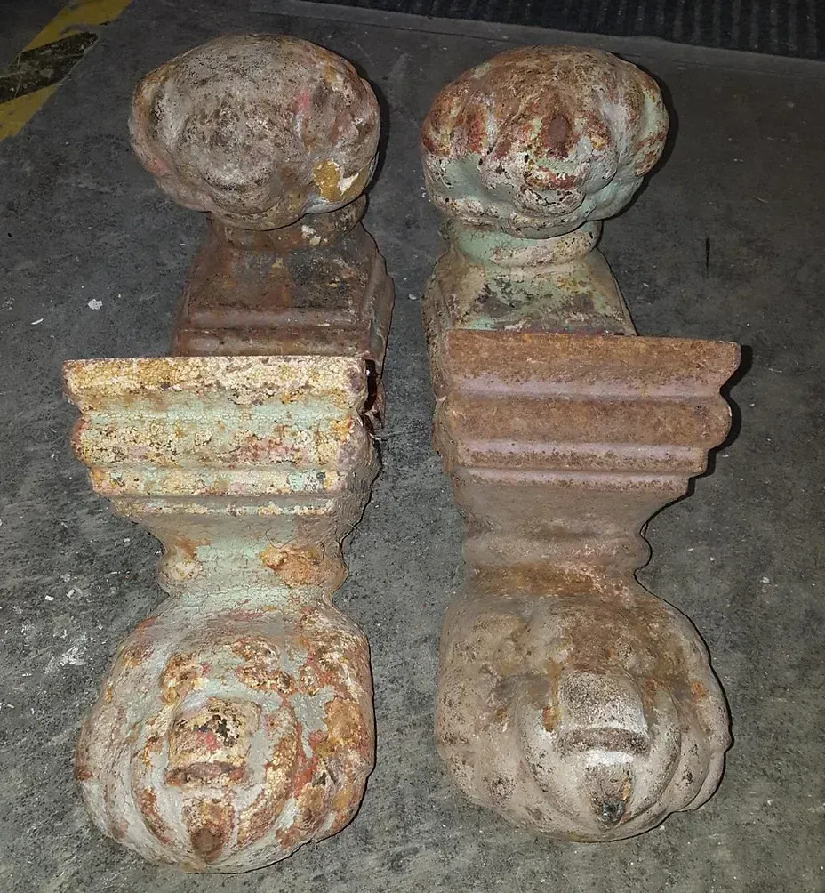 A pair of rusty metal pieces sitting on a concrete surface