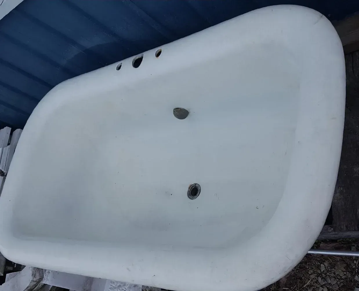 A white bathtub is sitting in front of a blue wall.
