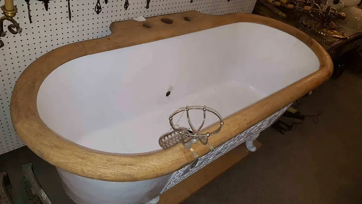 A bathtub with a wooden rim is sitting on the floor in a bathroom.