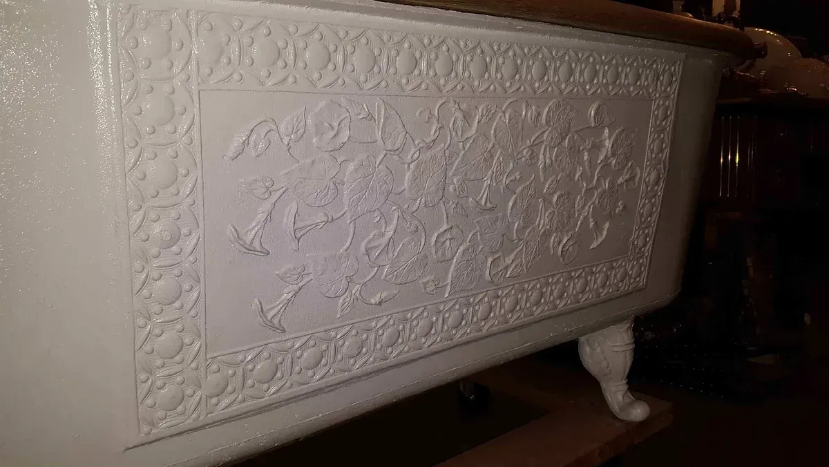 A white bathtub with a pattern on it is sitting on a wooden table.
