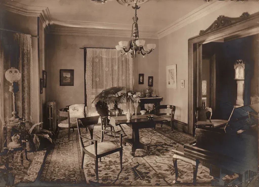 A black and white photo of a living room with a piano.