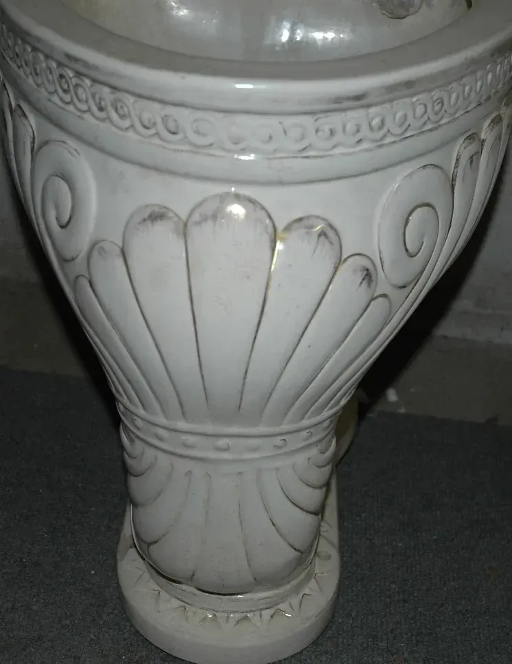A white vase with a shell design on it
