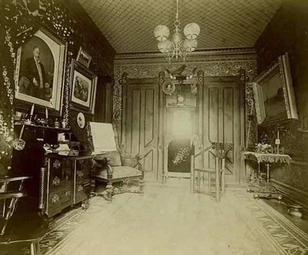 A black and white photo of a living room with furniture and a painting on the wall.
