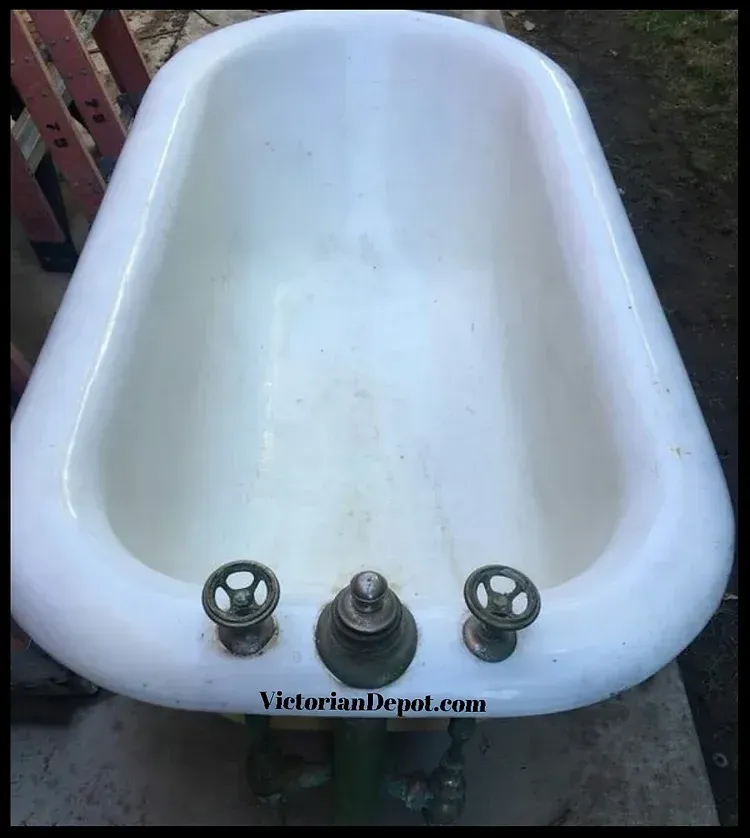 A white bathtub with three faucets is sitting on the ground.