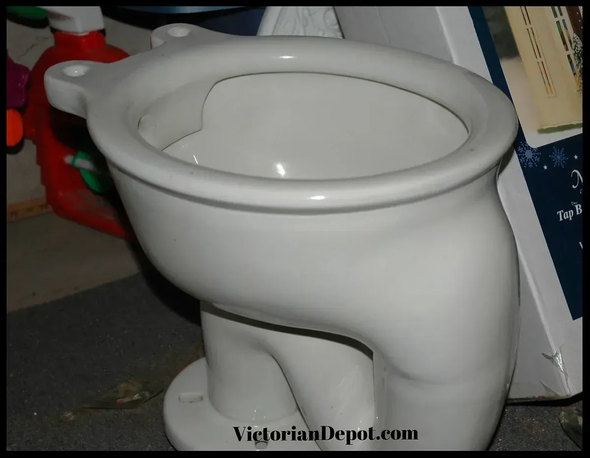 A white toilet sits in front of a book that says victoriandepot.com