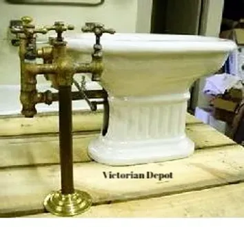 A bidet is sitting on top of a wooden table next to a bathtub.