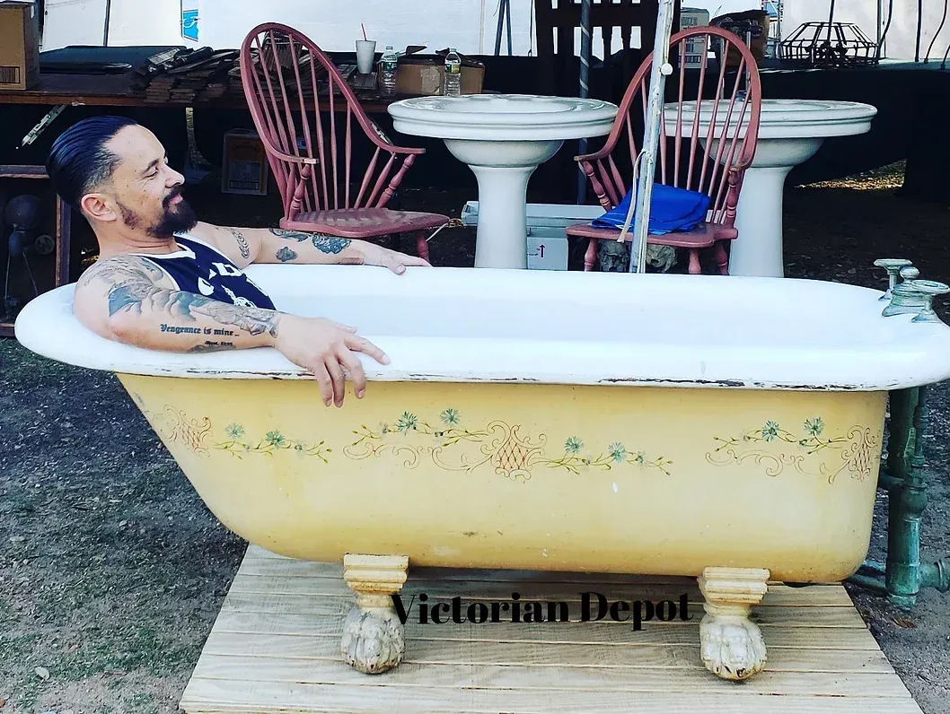 A man is laying in a bathtub that says victorian depot