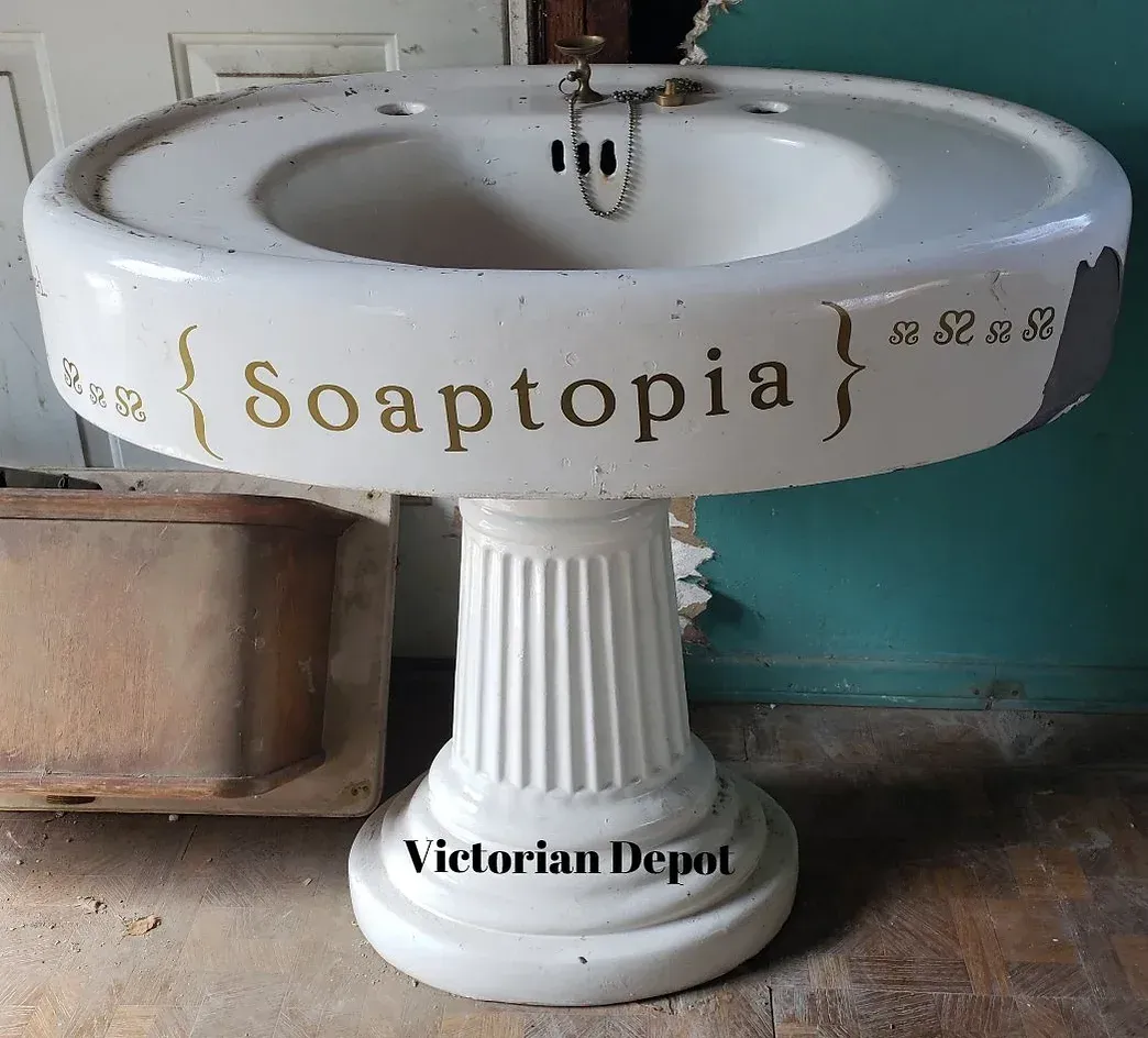 A white pedestal sink that says soaptopia on it