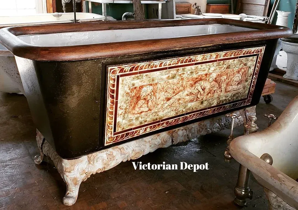 A bathtub with a floral design on the side is sitting on a wooden floor.