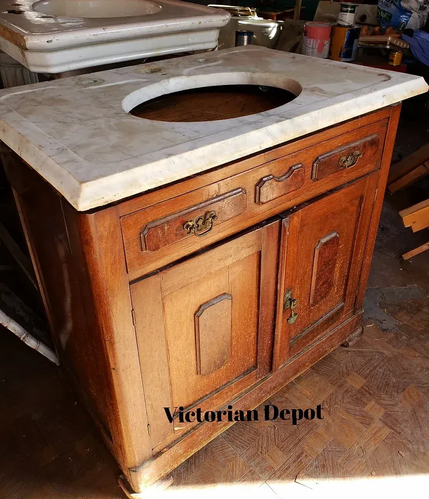A wooden vanity with a marble counter top and a sink.