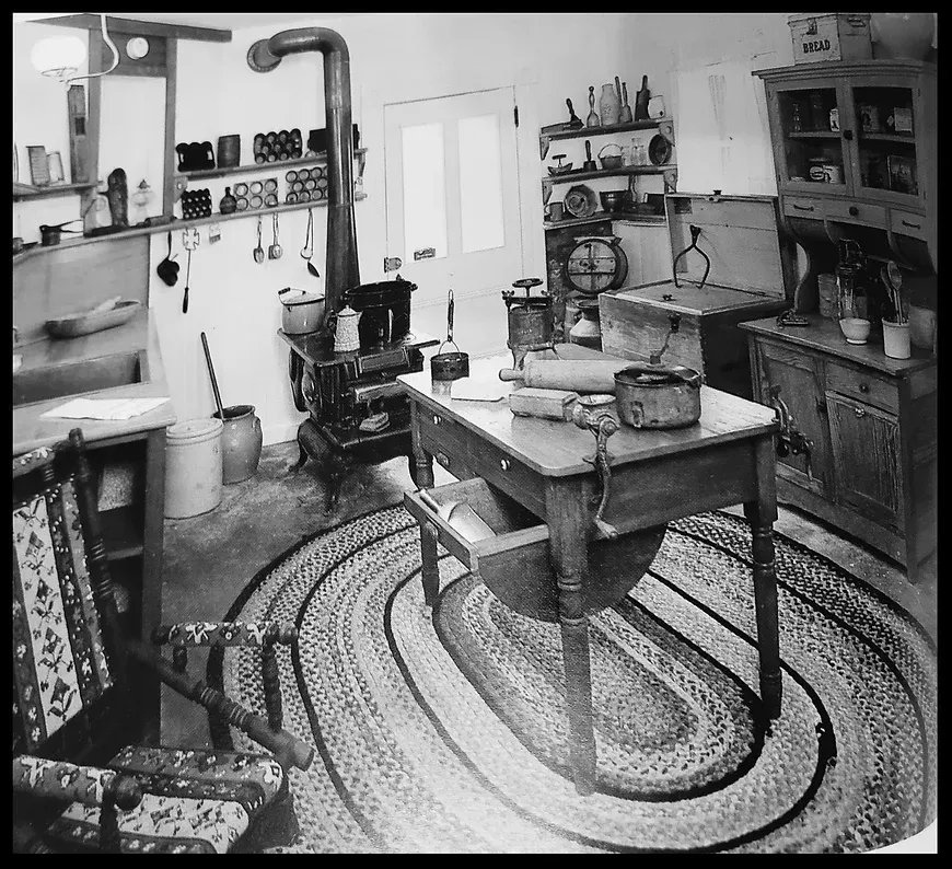 A black and white photo of a kitchen with a rug on the floor