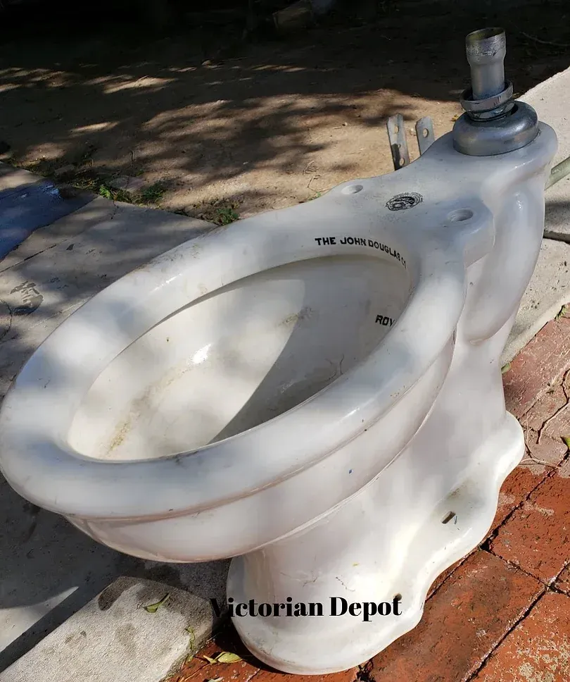 A white toilet is sitting on a brick sidewalk.