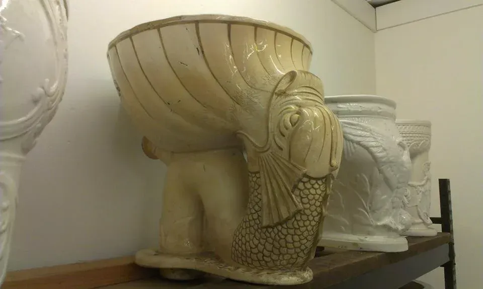 A toilet with a fish on it is sitting on a shelf next to other toilets.
