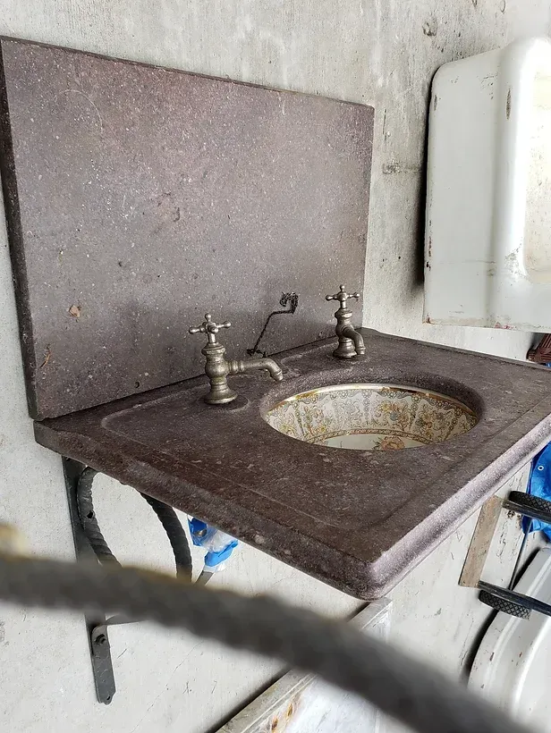A sink with two faucets on it is hanging on a wall.