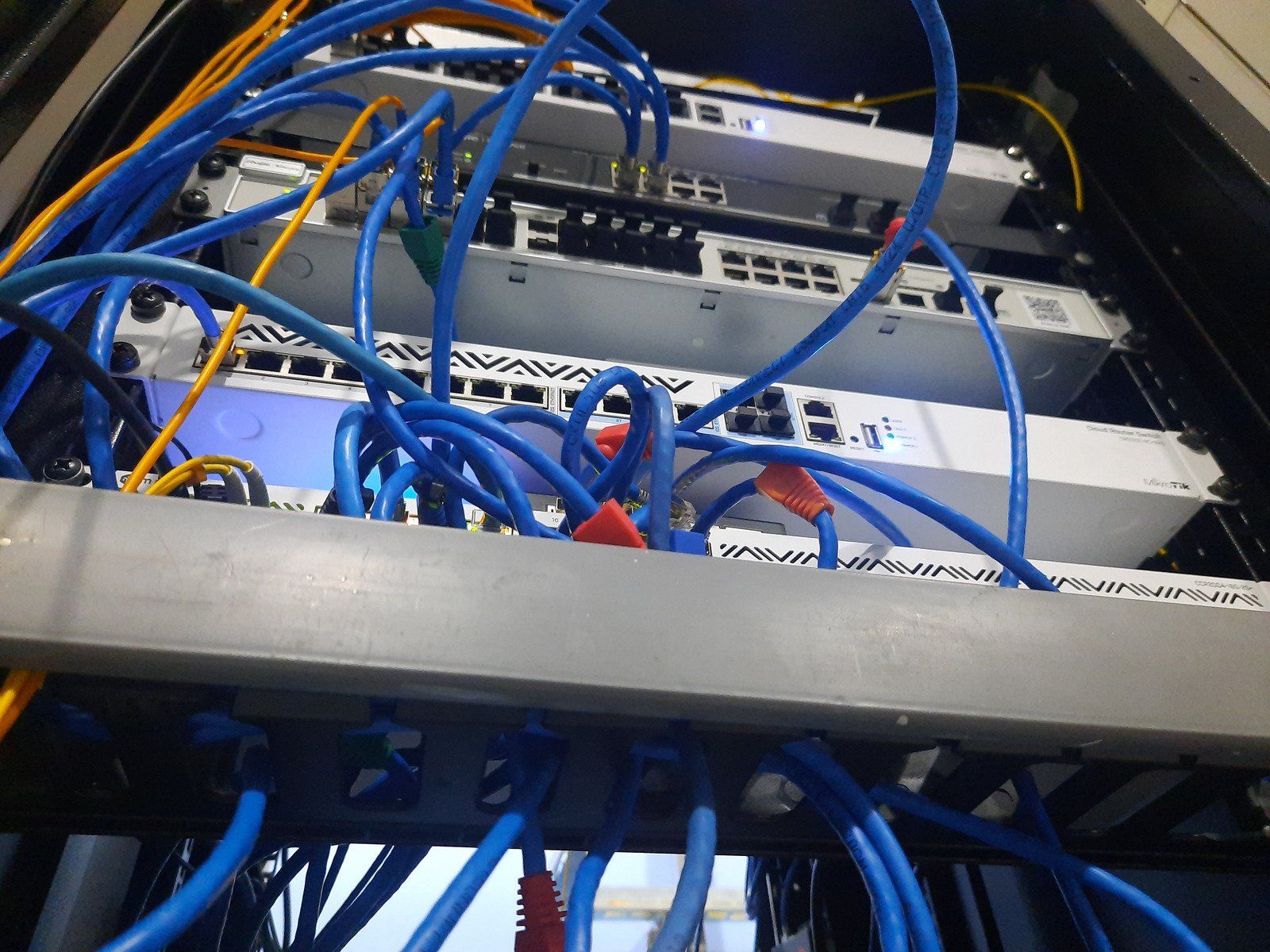Server rack with tangled blue network cables connecting multiple devices.