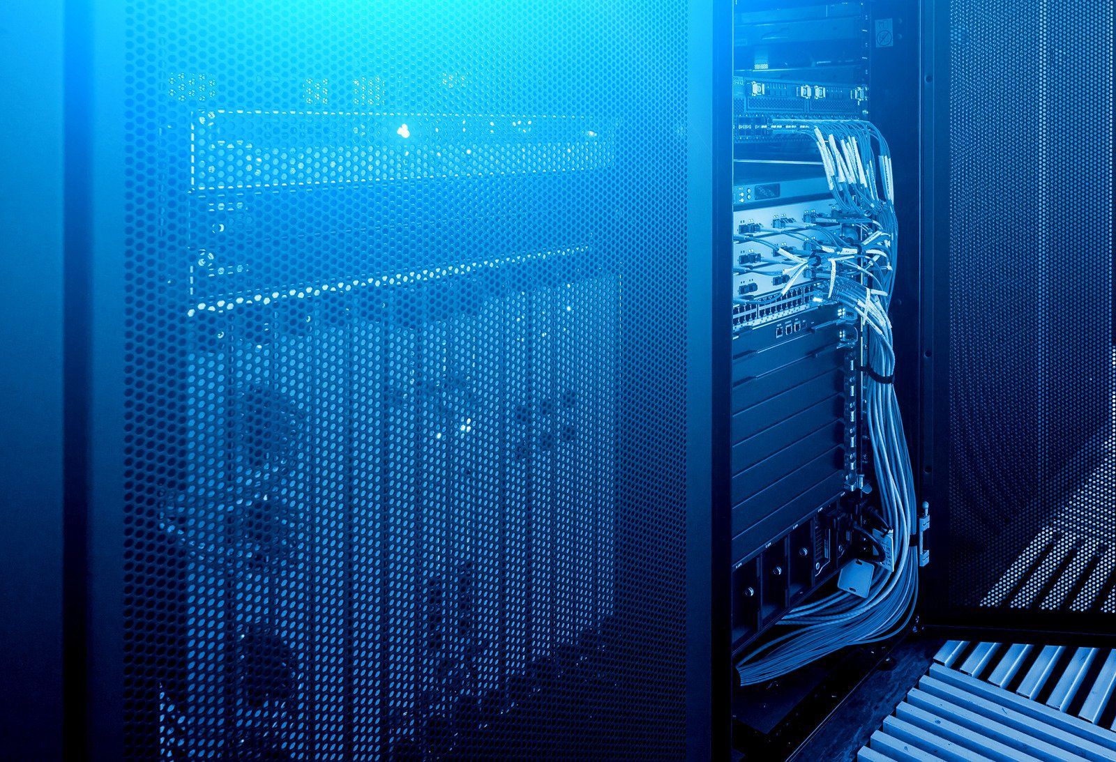 Server racks in a data center, blue-toned, with cables and lights.