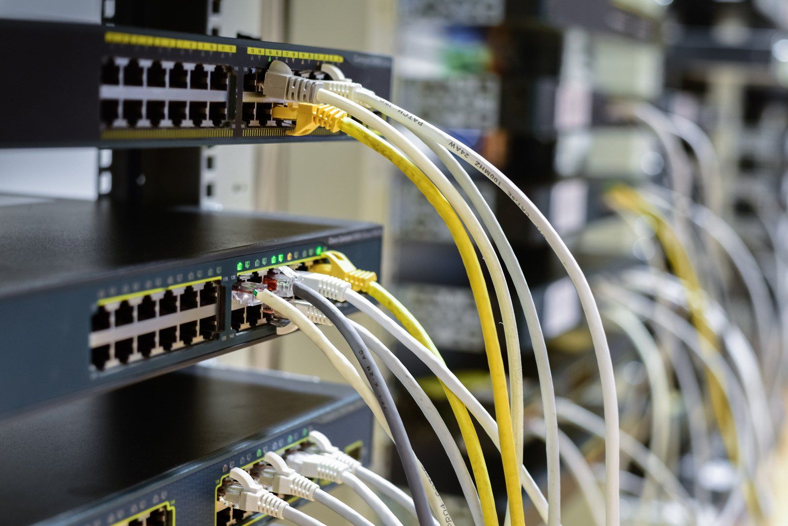 Network server rack with various colored Ethernet cables plugged in.