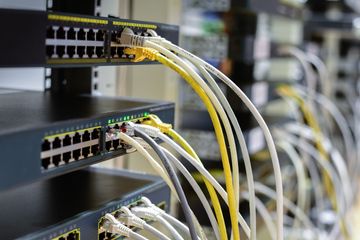 Network server rack with various colored Ethernet cables plugged in.