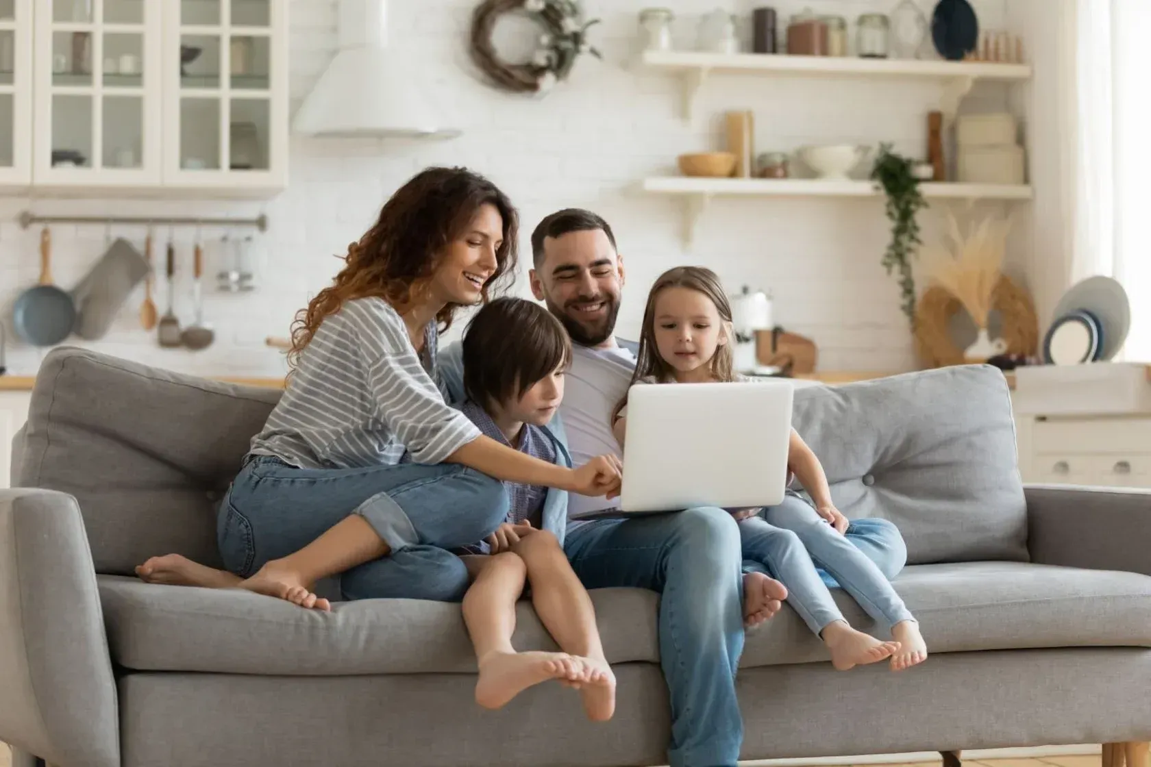 A family is sitting on a couch looking at a laptop.