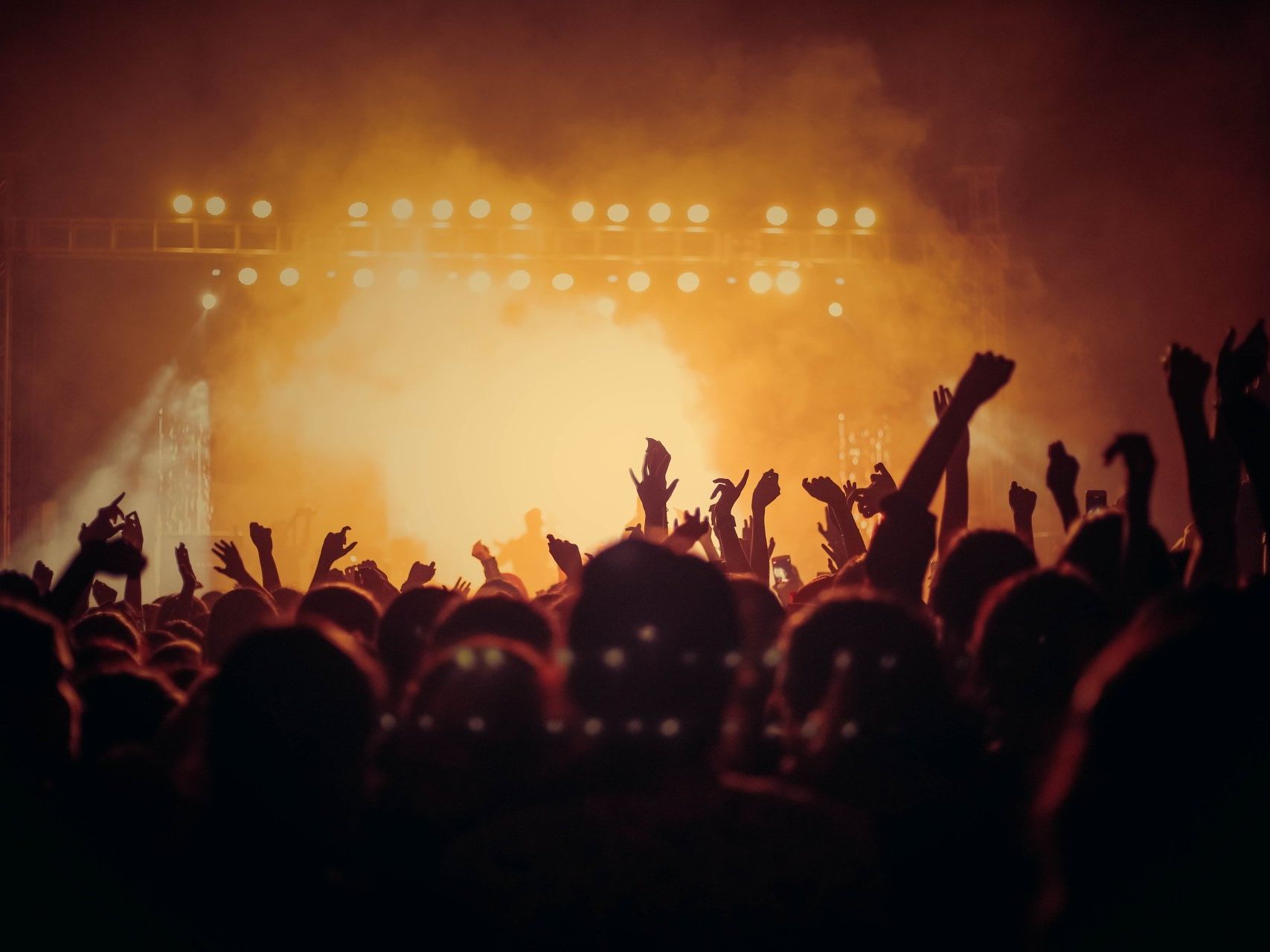 A crowd of people at a concert with their hands in the air.