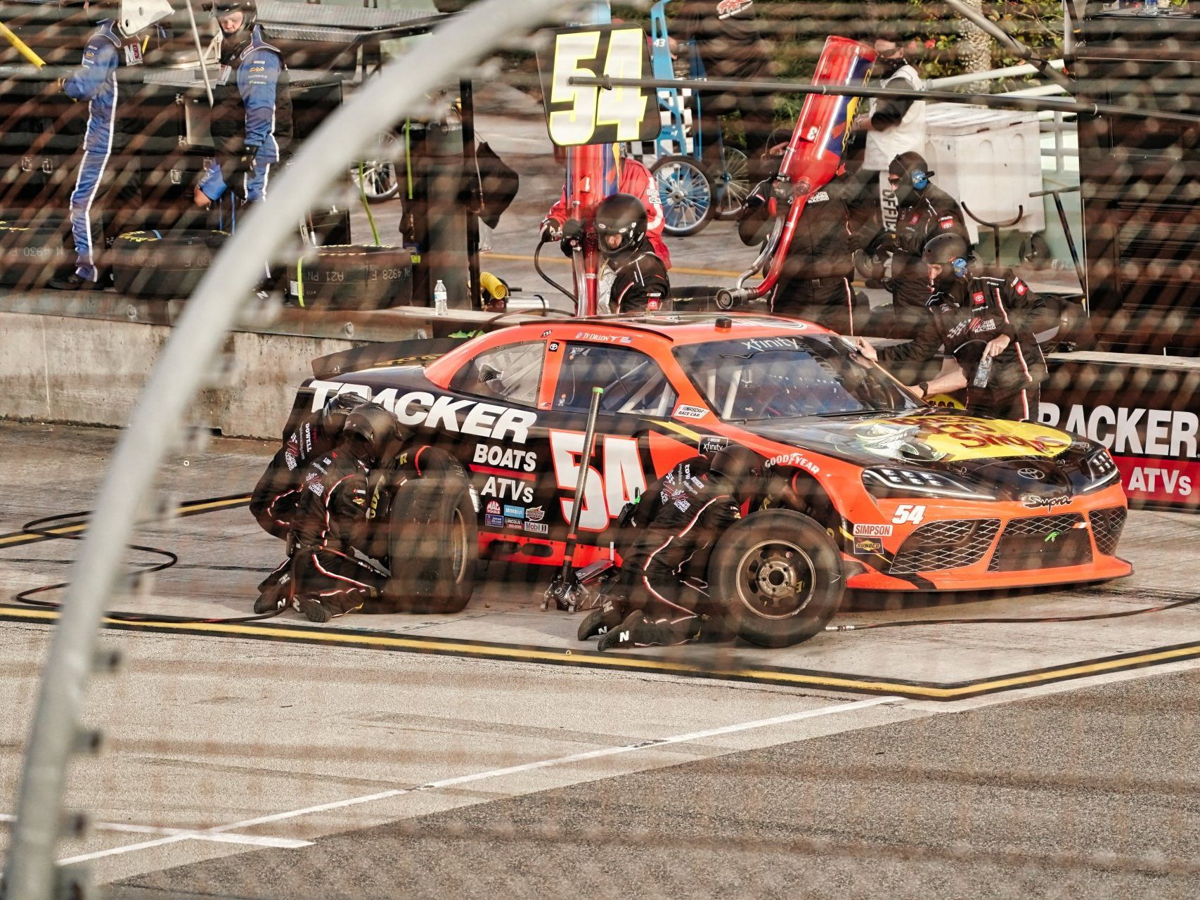 A race car with the number 54 on it is parked in a pit lane.