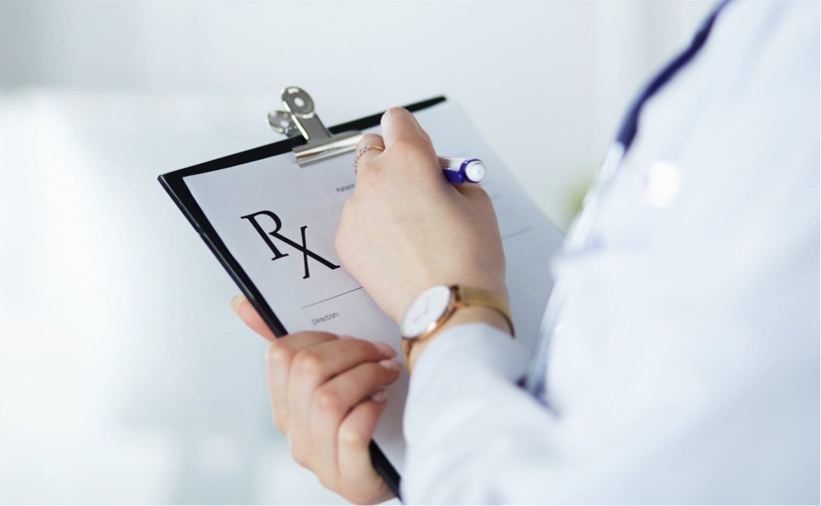 doctor writing on prescription clipboard