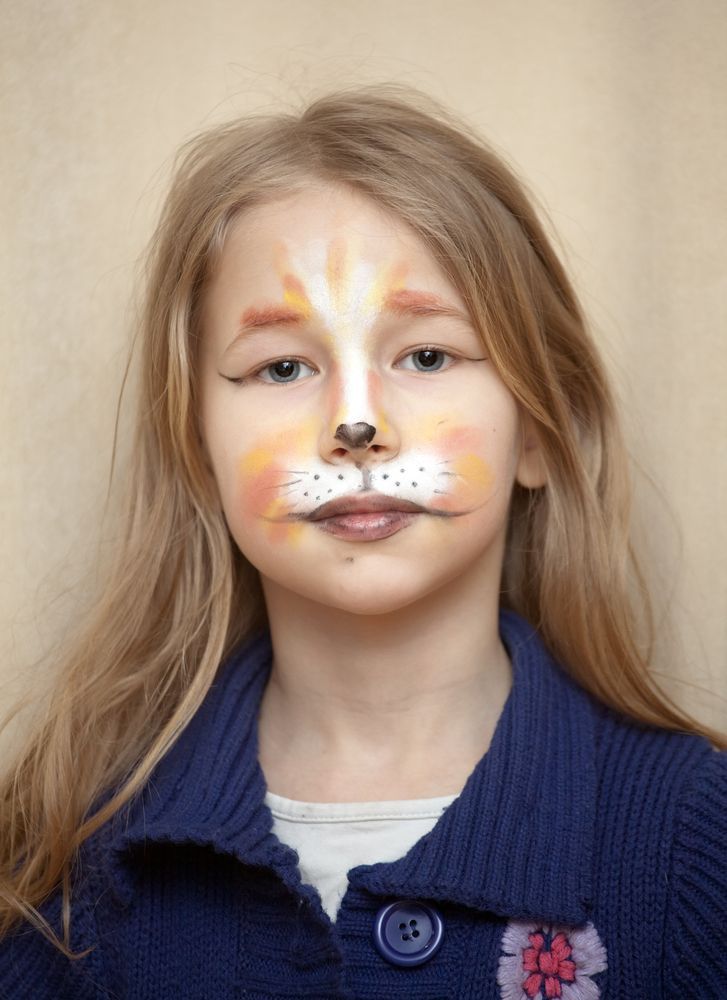 Girl with fox face paint, wearing a blue sweater.