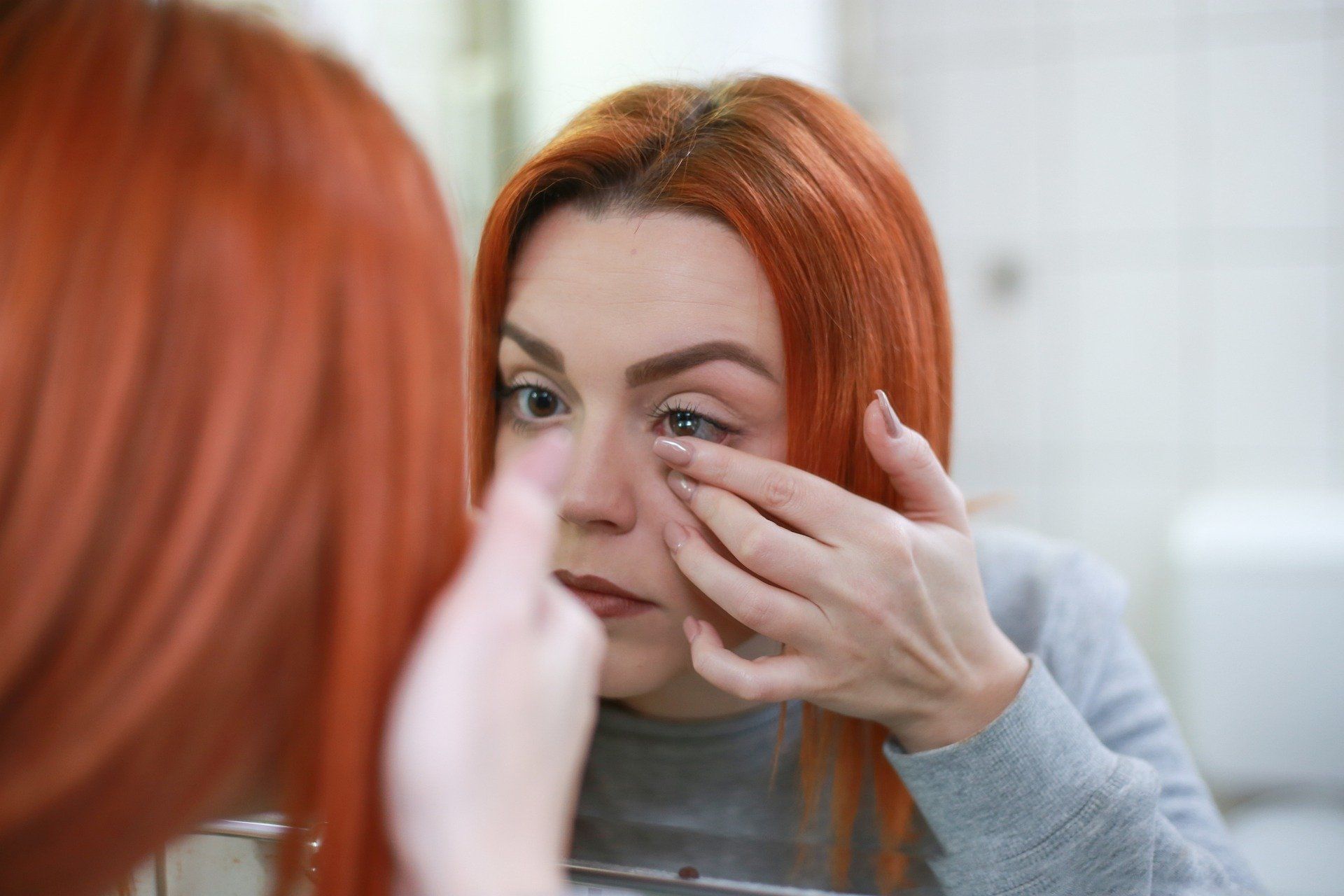 Woman putting contact lens in left eye