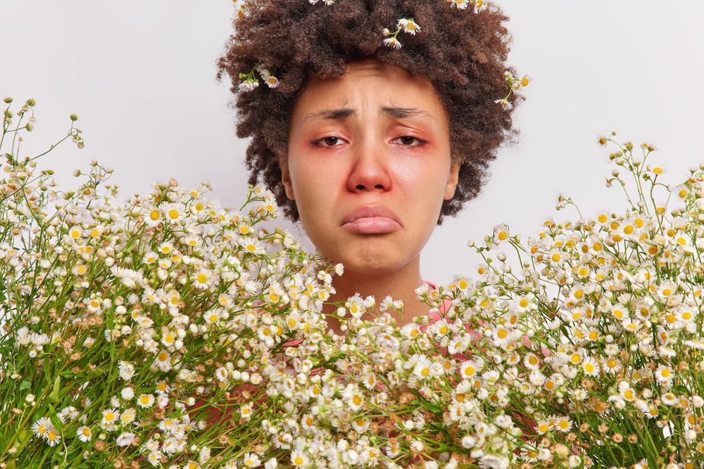 A woman with seasonal allergies holding a bunch of flowers.