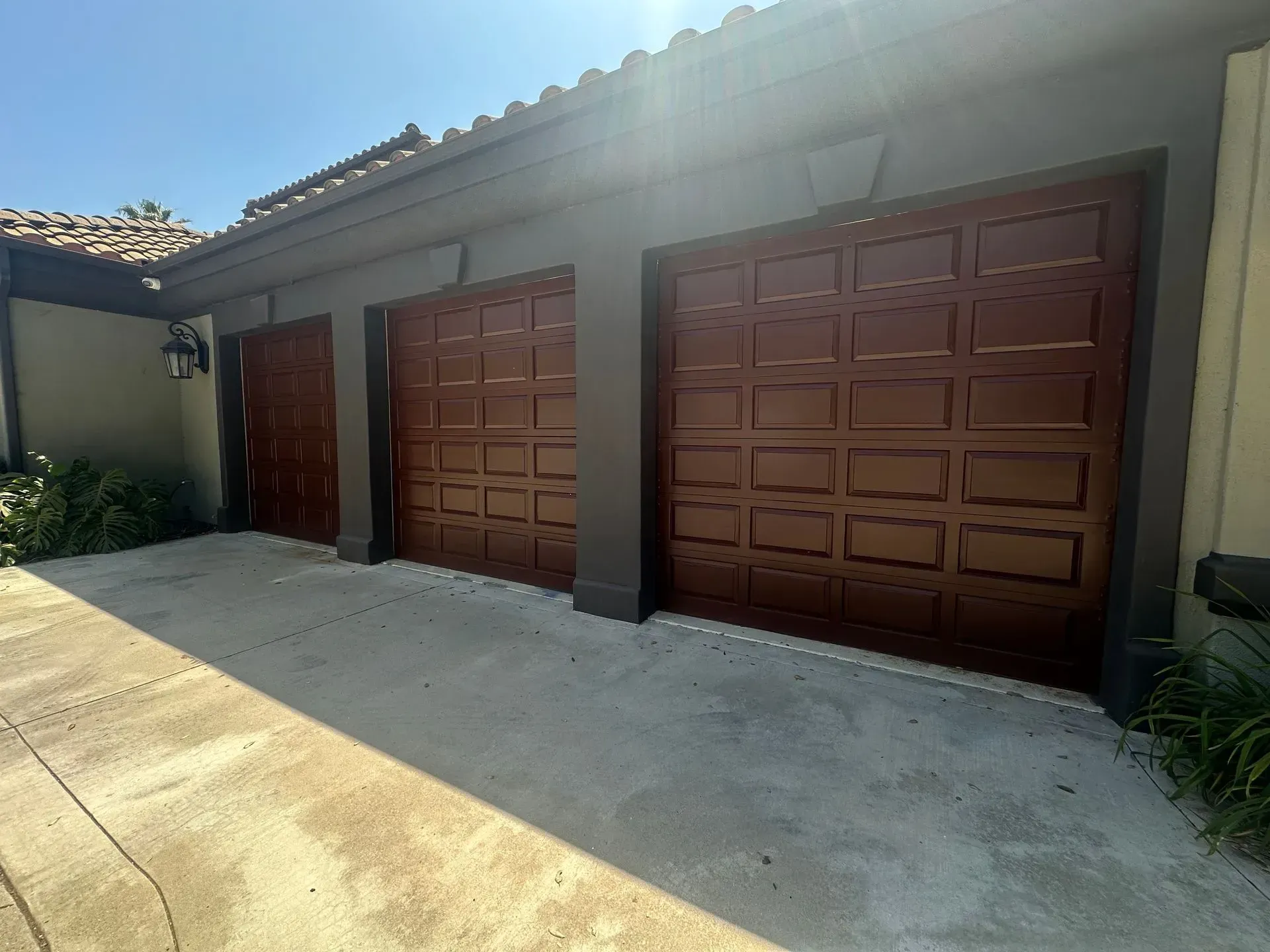 A row of brown garage doors on the side of a house.