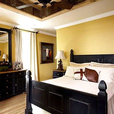 A bedroom with yellow walls and a black bed