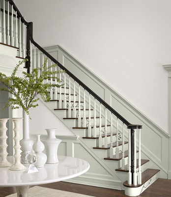 A white staircase with a black railing and a table with vases on it